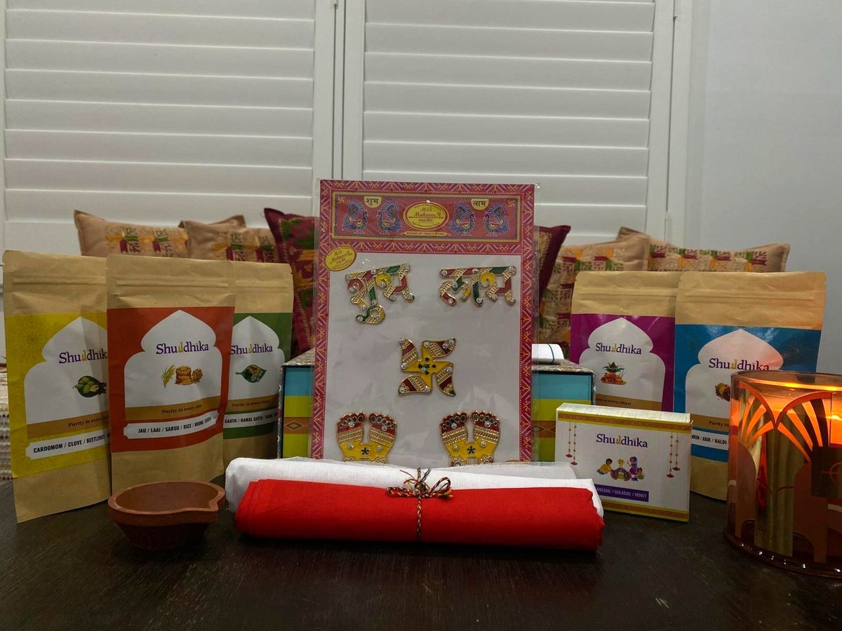 Everything in the Sampoorn Pooja Box laid out on a table: five pouches, cloth, a clay diya, stickers and bottles