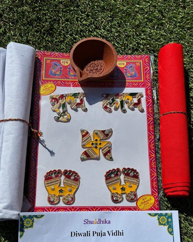 White and red cloth, a clay diya, and a sheet of pagaliya, Shubh Labh and swastik stickers