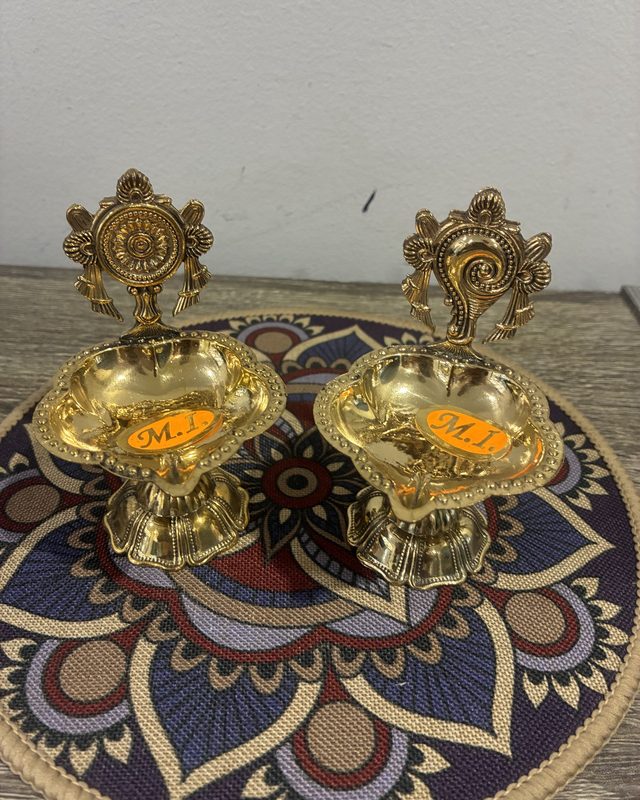 A pair of brass diyas with shankh and chakra backs