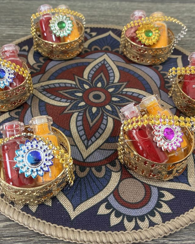 Small decorated baskets holding haldi and kumkum bottles