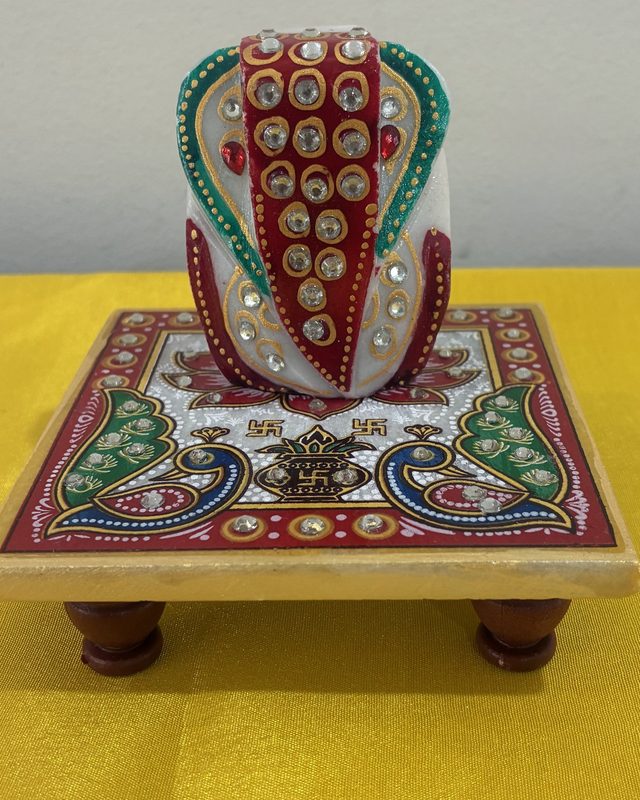 A hand-painted marble Ganesha seated on a painted chowki