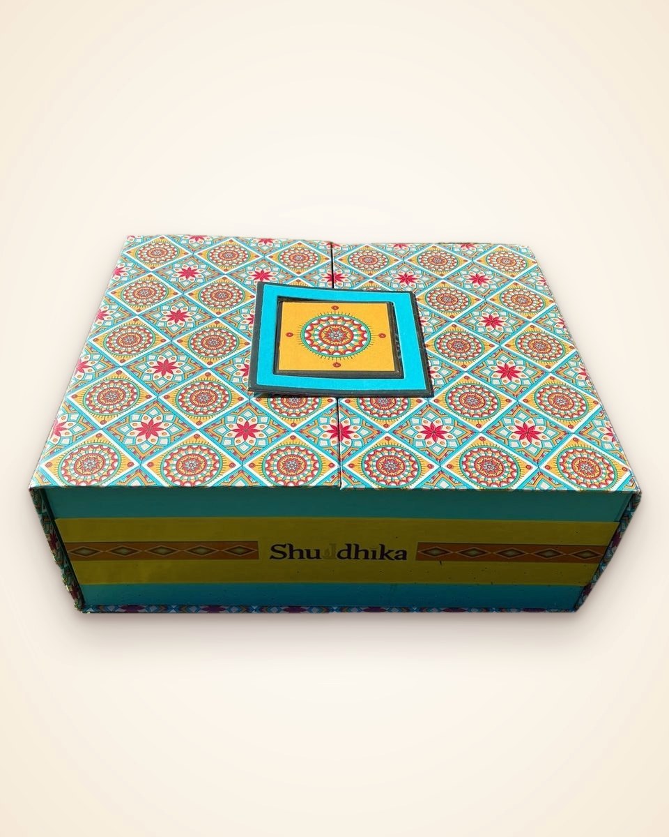 The Sampoorn Pooja Box, a patterned turquoise and yellow gift box with the Shuddhika name on the front