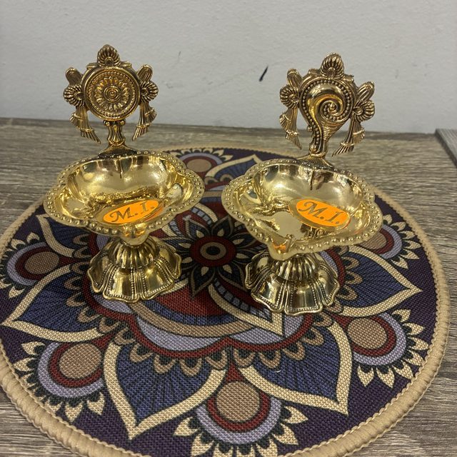 Brass diya pair on a mandala mat